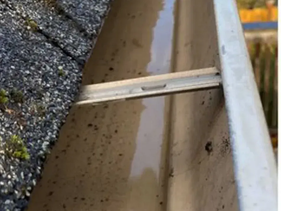 After cleaning: the same gutter cleared down to the trough, water sitting in it after flushing