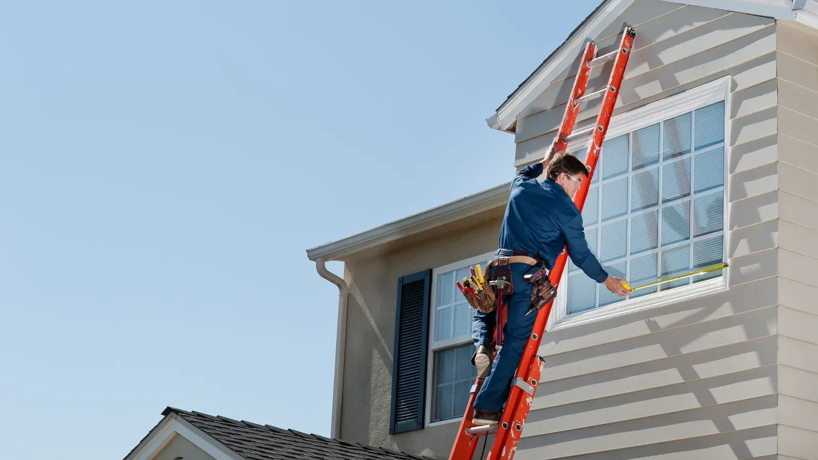 Ladder access to the upper storey of a house, worker in a tool belt