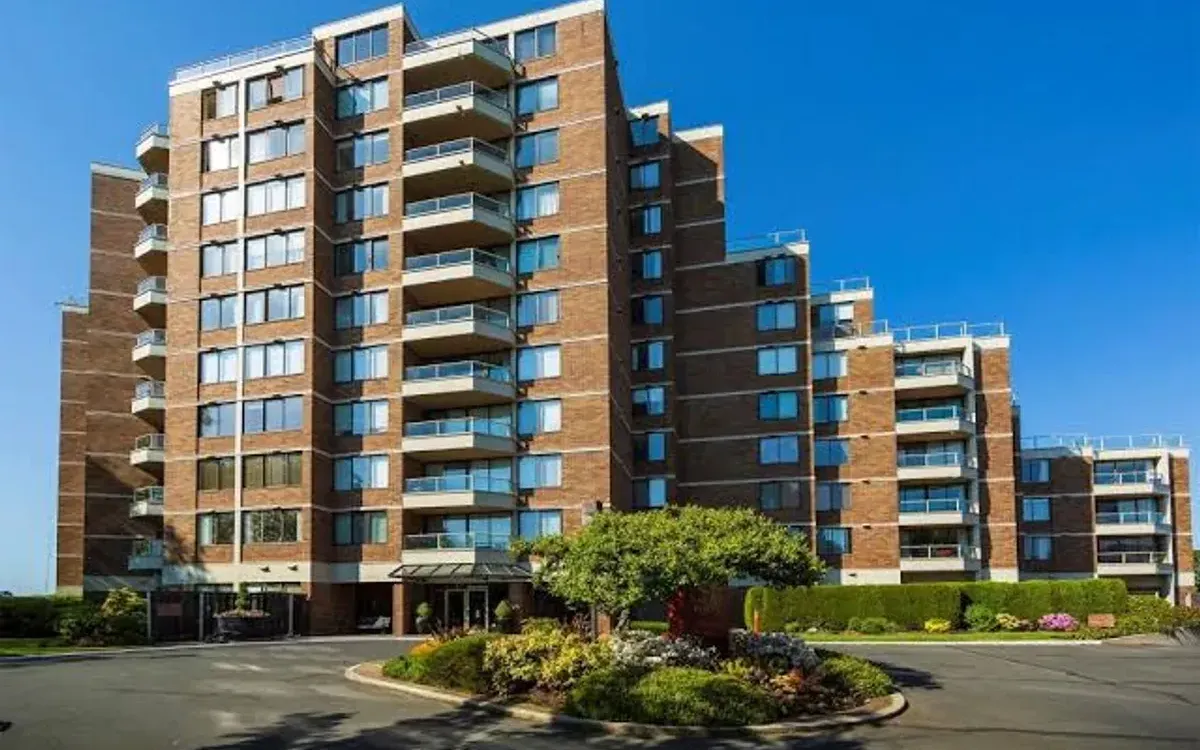 A tall multi-unit residential block seen from its front drive