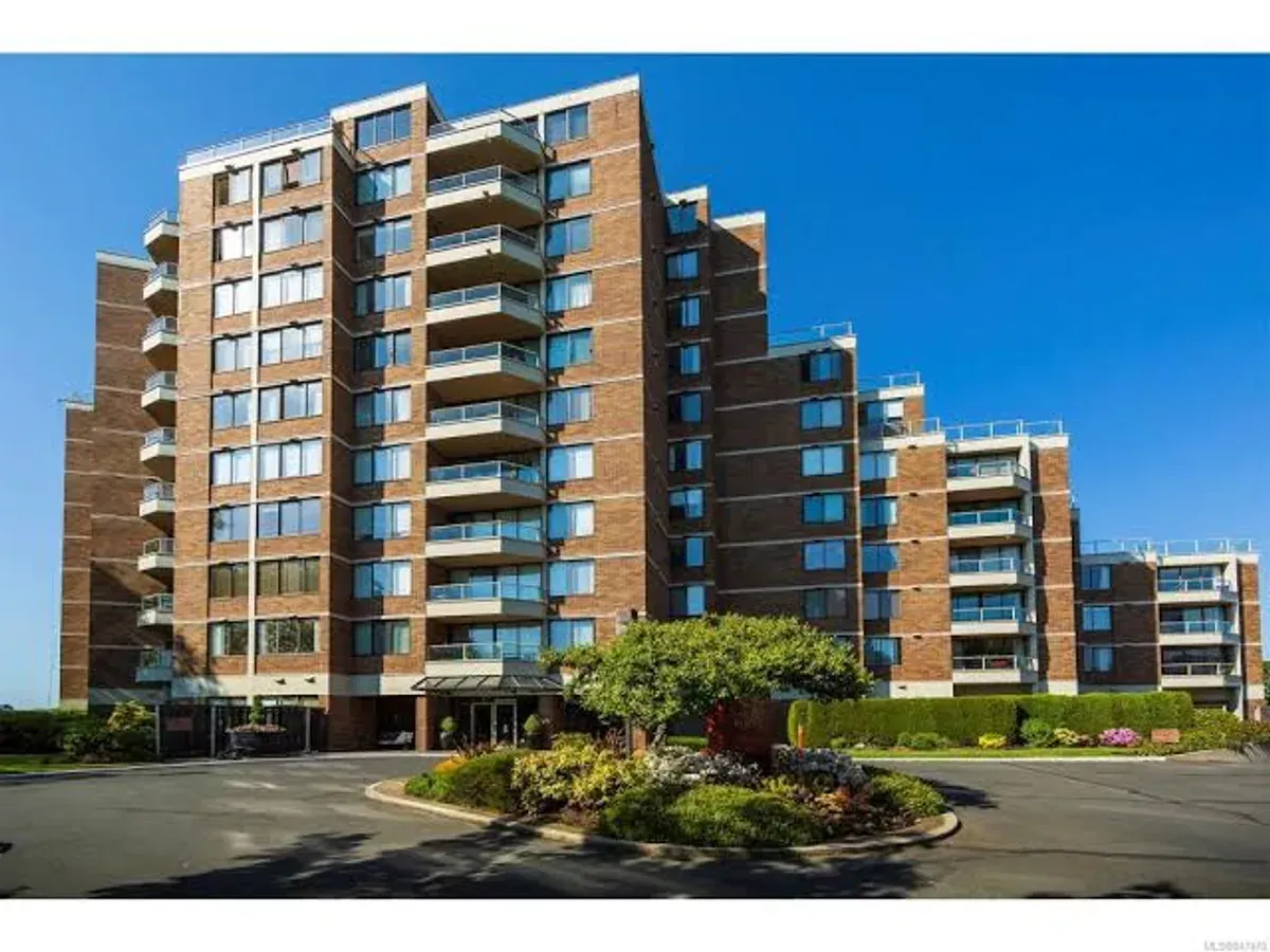 A multi-storey brick condo building with balconies on every floor
